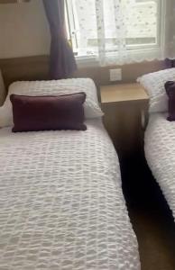 two twin beds in a room with a window at Caravan Church farm holiday village in Pagham