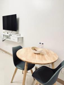 einem Holztisch mit 2 Stühlen und einem TV in der Unterkunft Snug Retreat with Cozy Vibes in Iloilo City