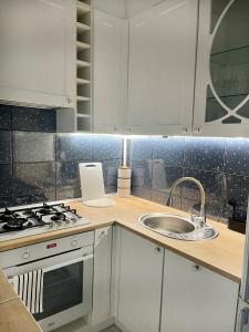 Una cocina blanca con fregadero y estufa. en Podmiejska 16, en Łódź 4 fotos más