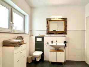 a bathroom with a sink and a toilet and a mirror at Ferienwohnung Moseltraum, bis zu 6 Pers, mit 3 Schlafzimmer und Panoramabalkon in Müden