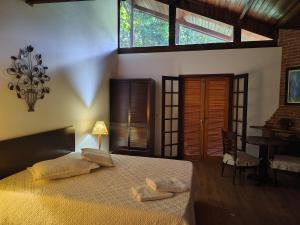 a bedroom with a bed and a table and windows at Pousada dos Pássaros in Santo Antônio do Pinhal +132 photos