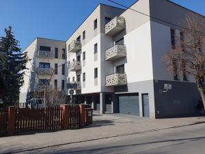 a white apartment building with a fence in front of it at Apartament Business & Parking Sienkiewicza in Leszno