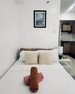 a bedroom with a white bed with two towels on it at Bright Airy Urban Escape in Iloilo City