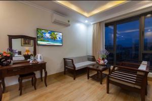 ein Hotelzimmer mit einem Schreibtisch und einem Tisch und Stühlen in der Unterkunft Coral Hotel Phu Quoc in Phu Quoc