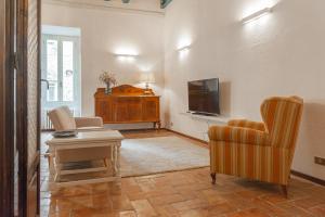 - un salon avec une télévision, un canapé et une chaise dans l'établissement City Center - Palazzo Pasini, à Pérouse