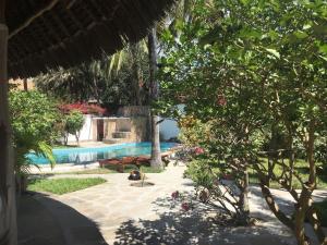 un complejo con piscina, árboles y flores en Villa Morosa, en Watamu