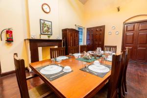 a dining room with a long wooden table with chairs at Shanthiniketan Heritage in Coonoor
