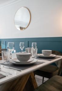 a table with plates and glasses and a mirror at Runway Hse Luxe 5 Bed, with King sized Beds, next to Aiport & NEC, JLR 5 mins in Marston Green +24 photos