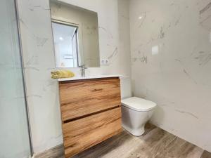 Un baño con inodoro, lavabo y espejo. en Beautiful renovated studio, en Castelldefels