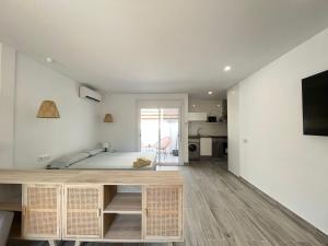 Un dormitorio blanco con una cama y un televisor. en Beautiful renovated studio, en Castelldefels