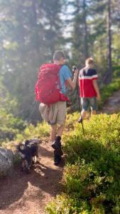 a man with a backpack walking on a trail with a dog at Veslekoia - Grandmas Cabin in Øksna