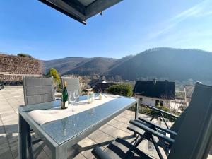 a table and chairs on a patio with mountains in the background at Ferienwohnung Sonnenterrasse, 1-4 Personen, 2 Schlafzimmer, große Terrasse in Müden