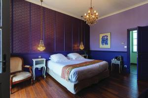 a bedroom with purple walls and a bed and a chandelier at Domaine de la Bedosse in Alès