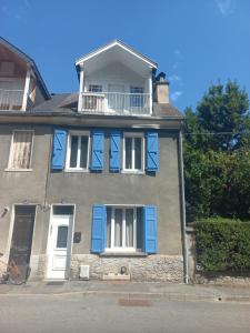 ein großes Haus mit blauen Fensterläden und einem Balkon in der Unterkunft Agréable maison de ville avec cheminée in Luchon