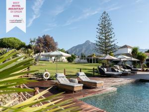 a pool with chairs and umbrellas next to a resort at Boho Club in Marbella