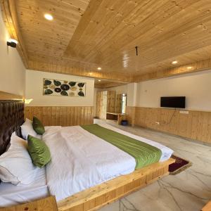 duże łóżko w pokoju z drewnianym sufitem w obiekcie MB Igloo Resort w mieście Manāli