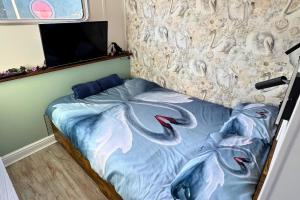 a bed with a blue comforter with dolphins on it at The Swan Flotel - Barton Marina in Burton upon Trent +22 photos