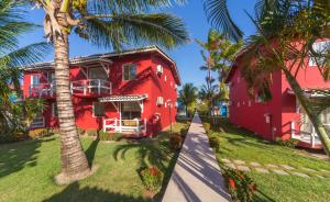 una casa roja con palmeras delante en Atlântida Park Hotel, en Porto Seguro