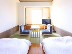 a room with two beds and two chairs and a desk at Dormy Inn PREMIUM Kushiro in Kushiro