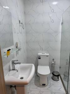 a white bathroom with a toilet and a sink at The Wood Hotel & Spa in Tashkent
