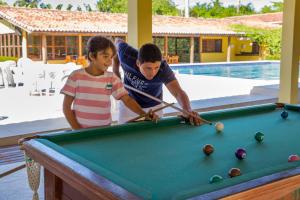 a man and a young girl playing billiard at Atlântida Park Hotel in Porto Seguro