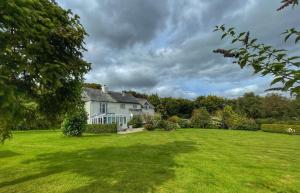 a white house with a large green yard at Cherryford House in Gidleigh