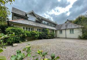 a large house with a gravel driveway in front of it at Cherryford House in Gidleigh