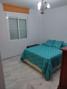 a bedroom with a bed with a green comforter and a window at Apartamento torrox in Torrox Costa +1 photo