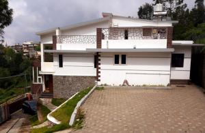 a white house with a balcony and a driveway at Greendale in Kotagiri