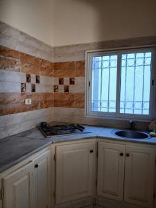 eine Küche mit Spüle und Fenster in der Unterkunft Appartement Nicolas Djerba route du phare in Taguermess