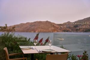 a table with two wine glasses sitting on a balcony at Lindos Royal Resort in Líndos