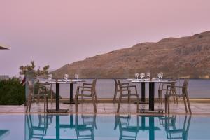 a table with wine glasses and chairs next to a pool at Lindos Royal Resort in Líndos