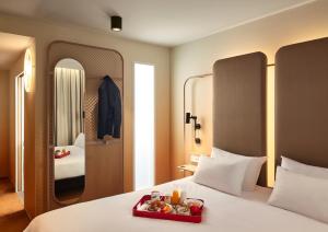a hotel room with a bed with a tray of food on it at You Hotels Deauville - Handwritten Collection in Deauville