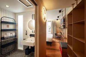 a hotel room with a bathroom with a bed and a sink at You Hotels Deauville - Handwritten Collection in Deauville