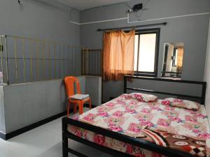 a bedroom with a bed and a orange chair at Shree Swa Cottage Revdanda in Alībāg
