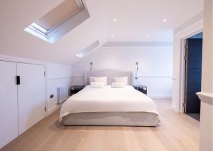 a white bedroom with a large white bed in it at The Stanley in Teddington