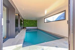 an indoor swimming pool in a house with a window at la villa iodée, le confort d une maison neuve équipée d une piscine intérieure chauffée toute l année, très proche des plus belles plages in Fouesnant