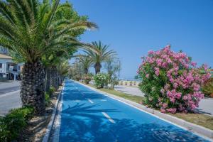 a swimming pool with palm trees and flowers on a street at Homiday - Residence Venere in Alba Adriatica