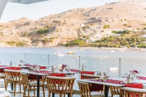 a restaurant with tables and chairs with a view of the ocean at Lindos Royal Resort in Líndos