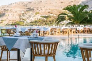 a restaurant with tables and chairs next to a pool at Lindos Royal Resort in Líndos
