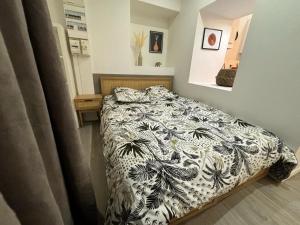 ein Schlafzimmer mit einem Bett mit einer schwarzen und weißen Decke in der Unterkunft Le Nid en Rotin Apartment in Montbéliard