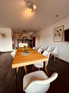 a dining room with a wooden table and white chairs at O107 XXL I 160m2 I Kamin I Balkon I 2 WC I Kücheninsel in Ibbenbüren