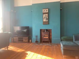 ein Wohnzimmer mit blauen Wänden, einem Sofa und einem TV in der Unterkunft Gavin's Sea Pad in St. Leonards