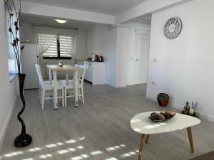 a white living room with a table and a kitchen at Zen Apartment in Bacău +5 photos