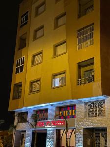 a yellow building with a sign in front of it at Un appartement cosy in Oujda