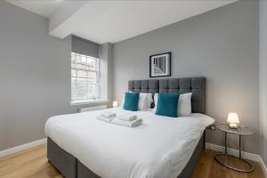 a bedroom with a large white bed with blue pillows at Destiny Scotland Apartments at Canning Street Lane in Edinburgh