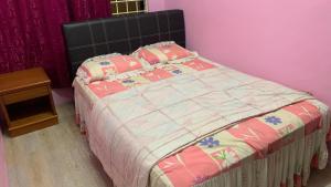 Una cama en un dormitorio con una pared rosa. en Homestay Bintang Maya, en Sungai Petani