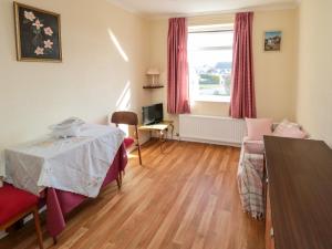 a living room with a table and a bed and a window at Sycamore in Filey