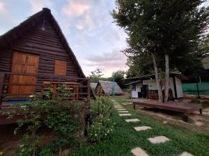 a wooden cabin with a bench and a tree at Phu Aunna in Ko Phayam