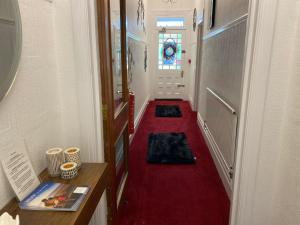 a hallway with a red floor and a red carpet at Villa Guest House in Porthcawl